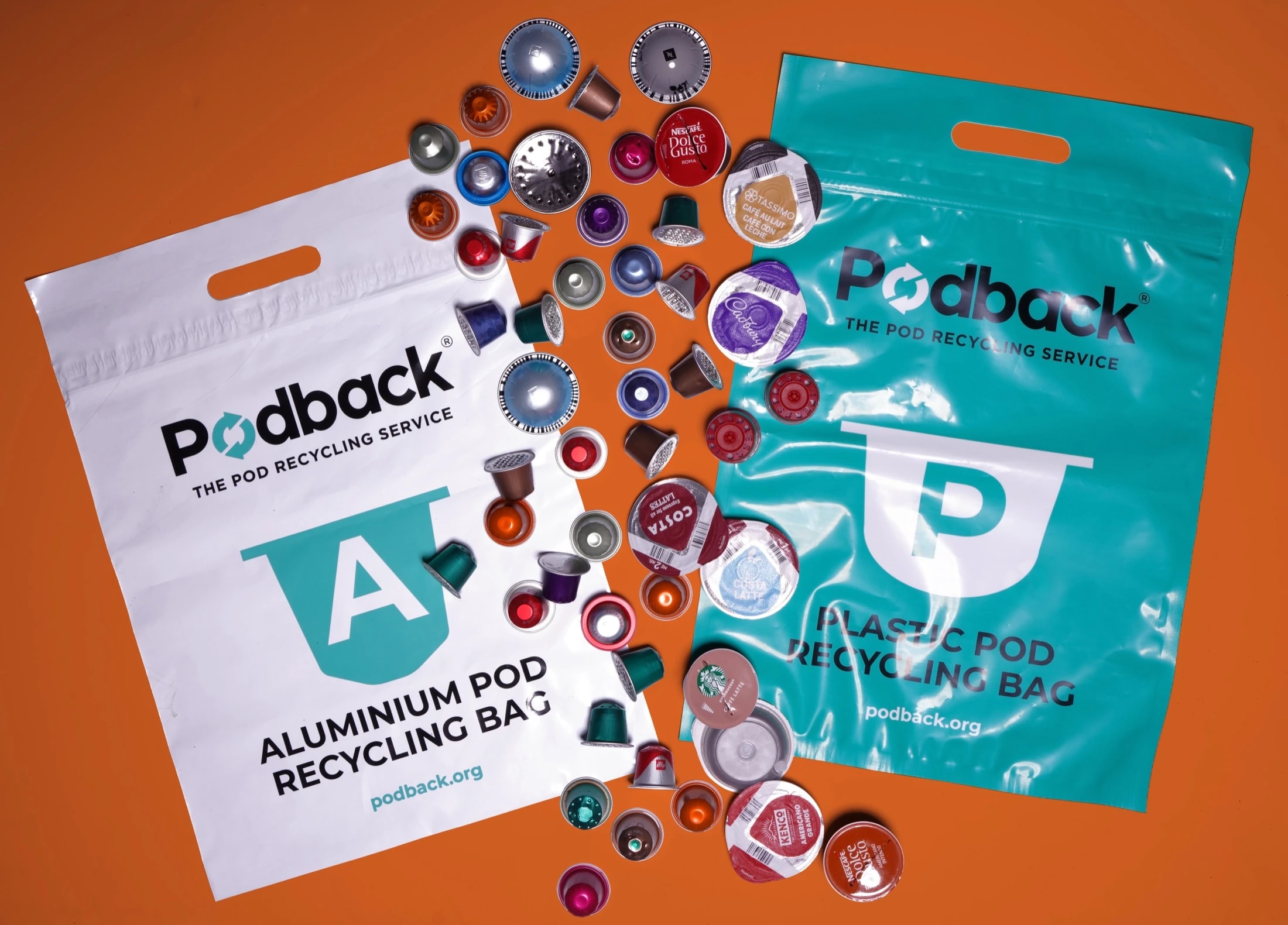Podback aluminium and plastic pod recycling bags surrounded by used coffee pods on an orange background